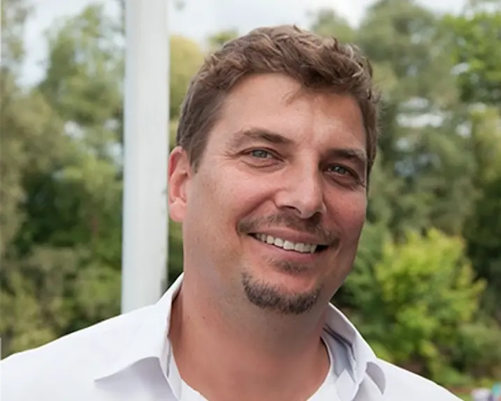 Hannes Einfalt was photographed in nature. He is smiling and wearing a white shirt.